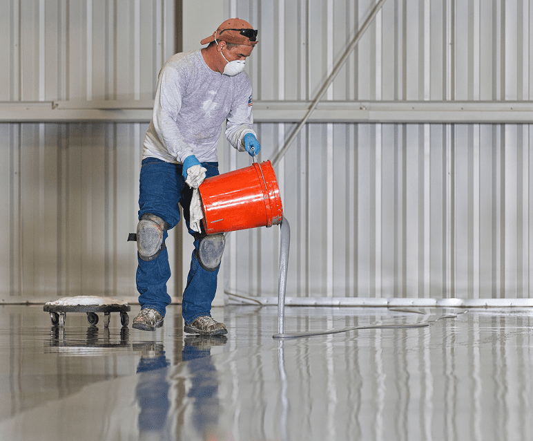Worker pouring liquid onto a floor.