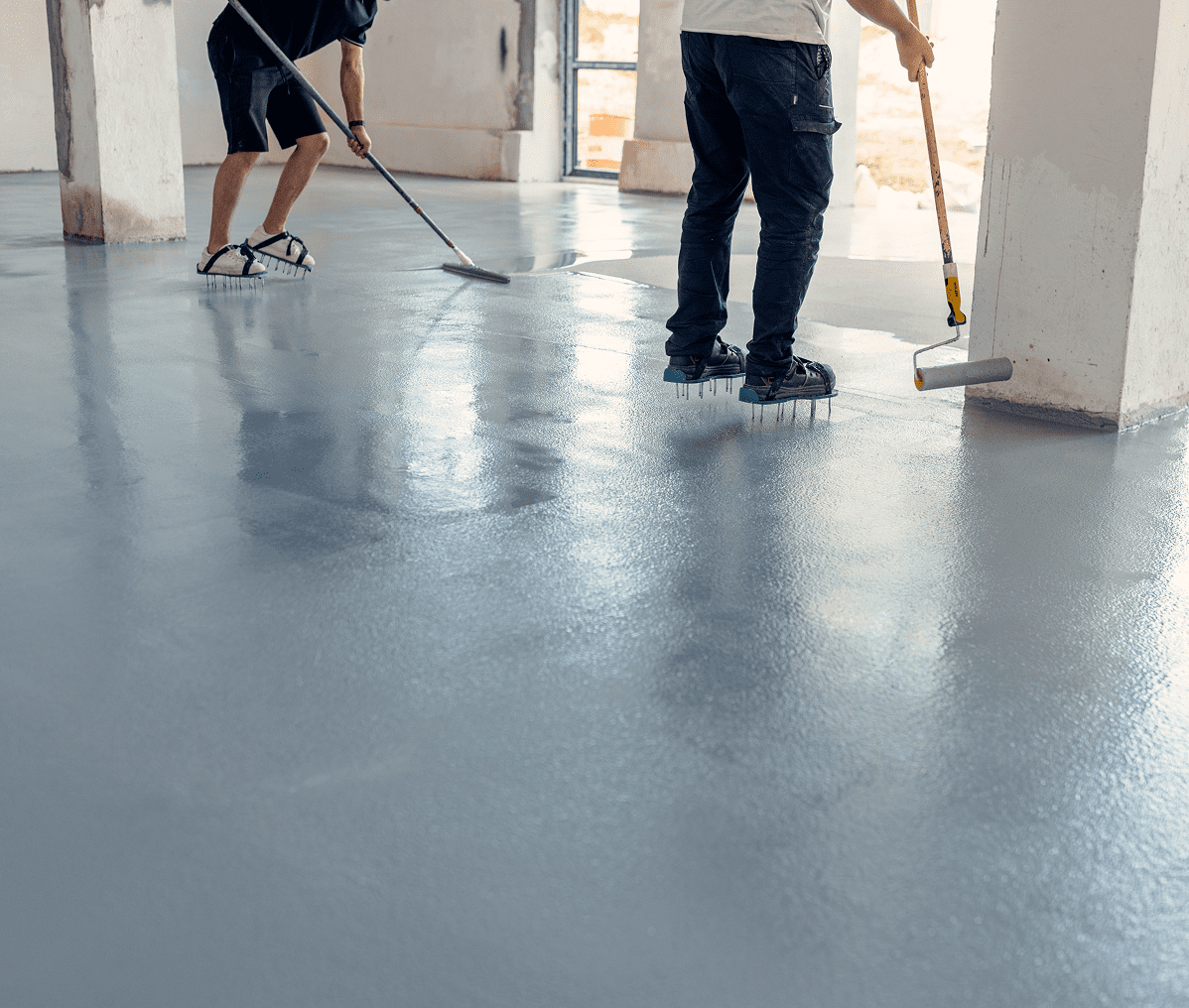 Two workers applying floor coating indoors.