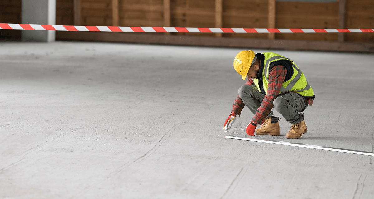 Construction worker measuring concrete floor.