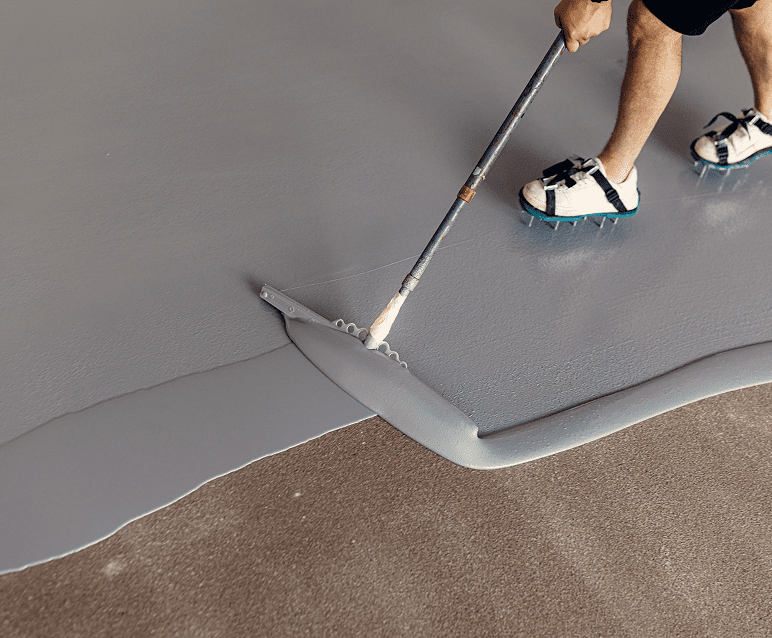 Applying gray epoxy floor with roller.