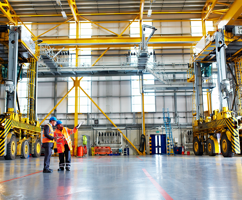 Workers in industrial warehouse with machinery.