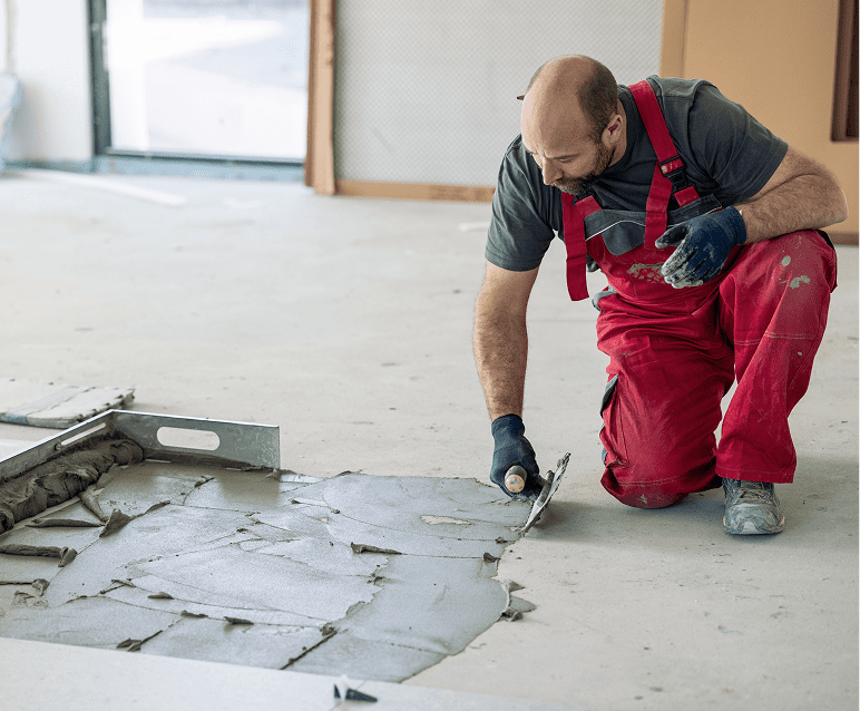 Worker applying mortar to concrete floor.
