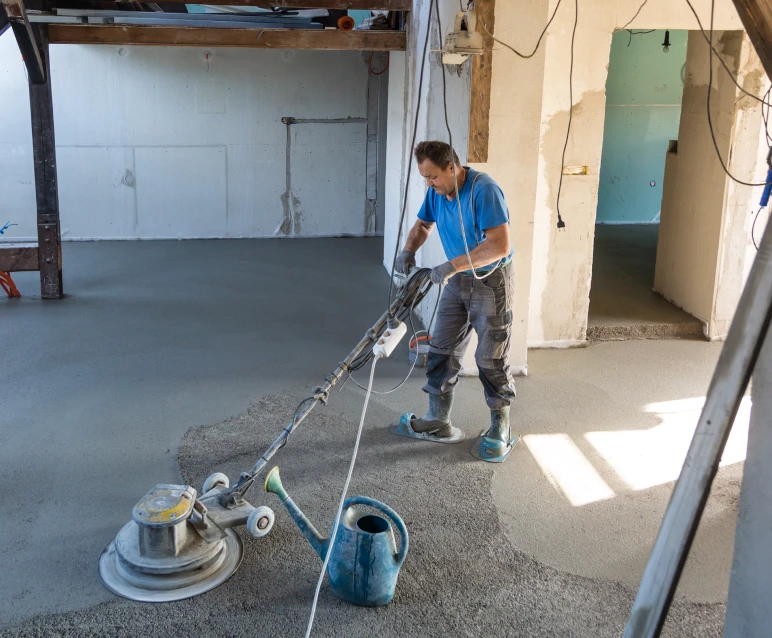 Worker smoothing concrete floor with machine.